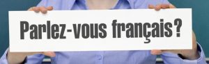 A person holds up a sign that says "Parlez-vous français?"