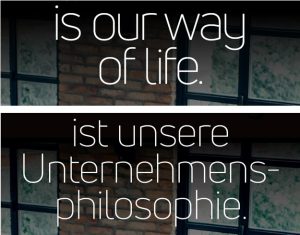 A snippet of an English poster that says "is our way of life." alongside the German version that hyphenates the word "Unternehmensphilosophie" across two lines